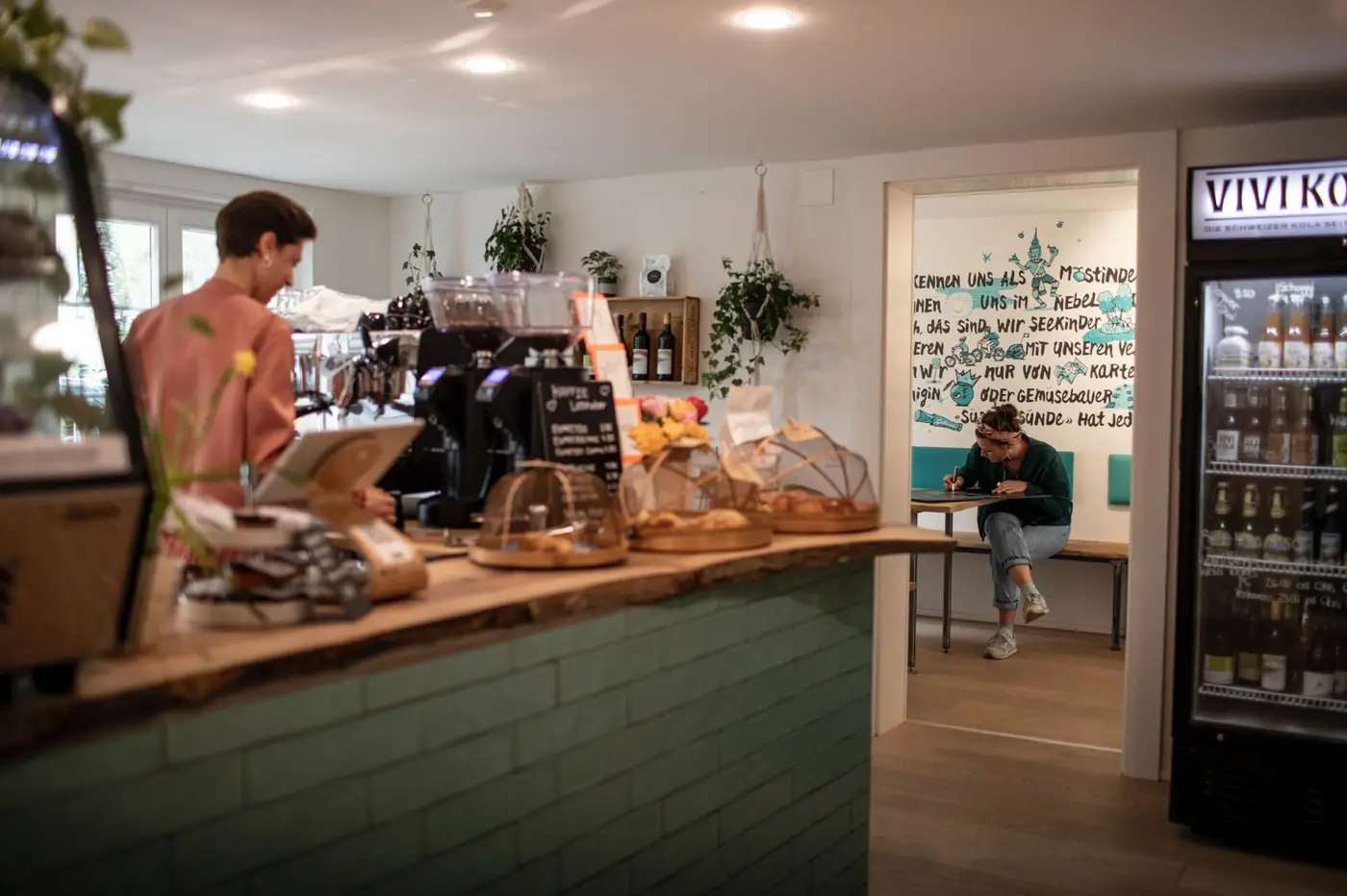 Das Café im Begegnungshaus: Holztheke, Kuchen und hinten der Raum mit der Seekinder-Wand
