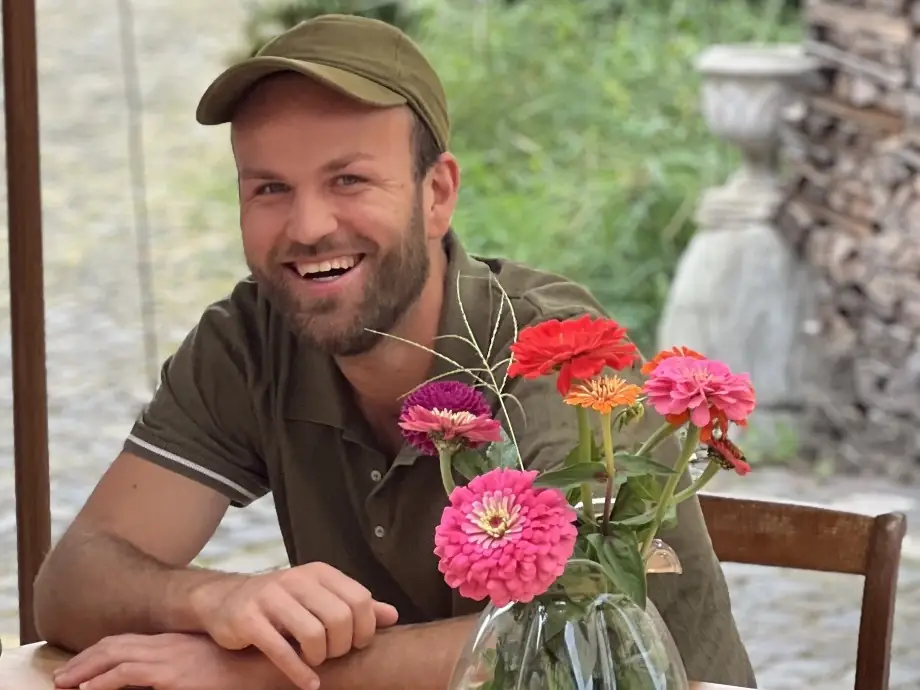 Joël Theubet lachend am Holztisch mit Blumen